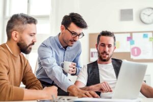 group-of-young-businessmen-with-laptop-working-in--FUBAM8V