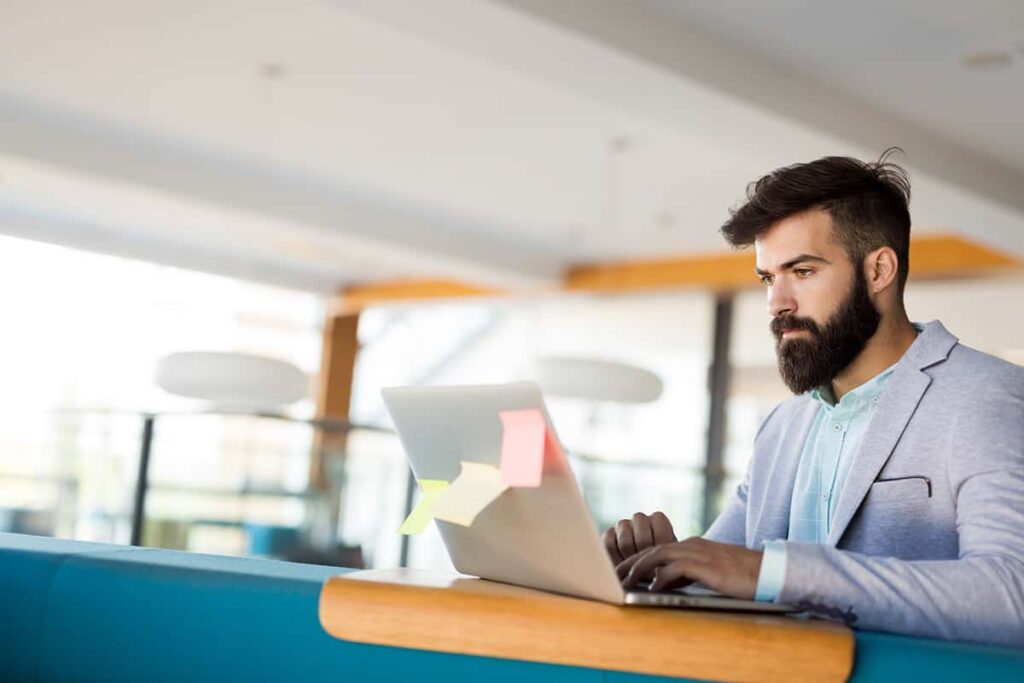 handsome-businessman-working-on-laptop-in-office-NQ43U75