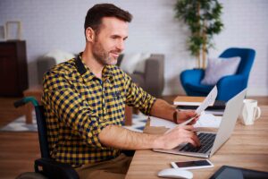 side-view-of-disabled-businessman-using-laptop-in--3RHUGV2